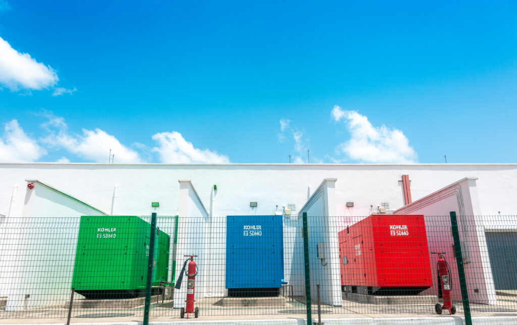 This image showcases the exterior of the Onix Data Centre in Accra, Ghana. The focus of the image is on the three colour-coded backup generators, representing the robust power backup system in place to ensure continuous service and data accessibility.
